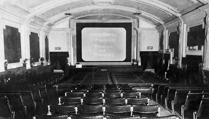 This picture postcard from 1912 shows the hard front seats and a silent screen.